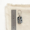 A snowflake obsidian earring next to a ruler for size reference