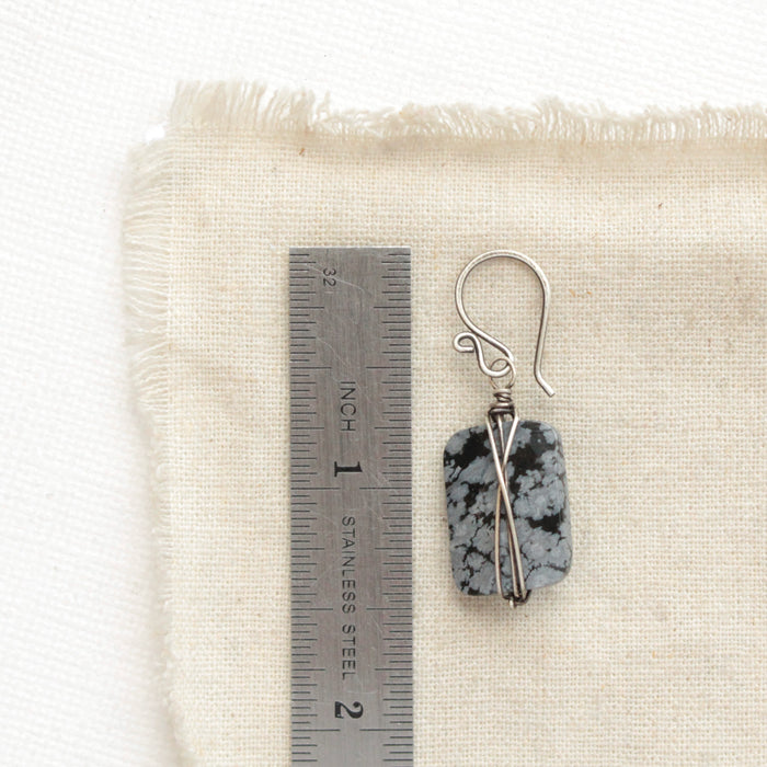 A snowflake obsidian earring next to a ruler for size reference