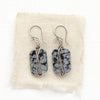 The snowflake obsidian earrings styled on tan linen
