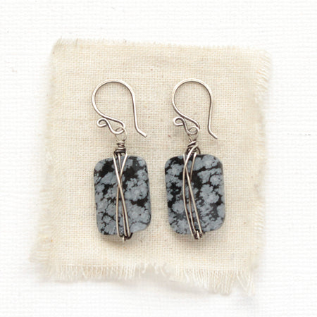 The snowflake obsidian earrings styled on tan linen