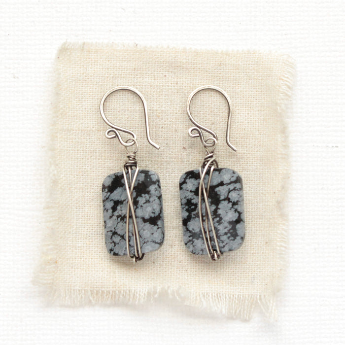 The snowflake obsidian earrings styled on tan linen