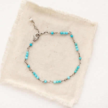 The wrapped turquoise bracelet styled on tan linen