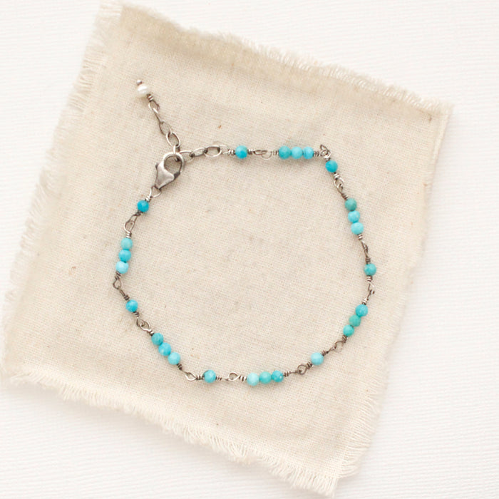 The wrapped turquoise bracelet styled on tan linen