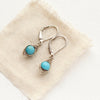 The silver wrapped turquoise earrings styled on tan linen