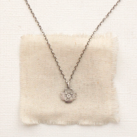 The zuni cross necklace styled on tan linen