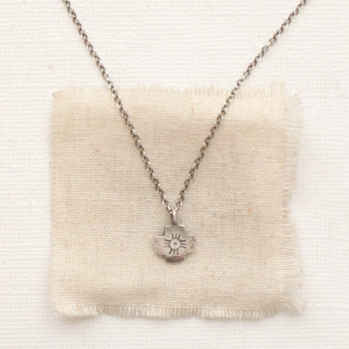 The zuni cross necklace styled on tan linen