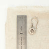 A zuni cross earring next to a ruler for size reference
