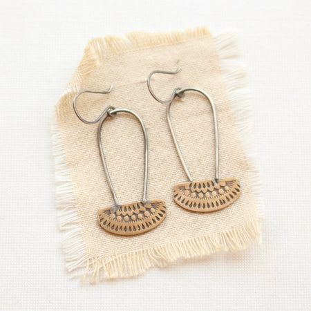 The stamped bronze and silver long loop asmi earrings styled on tan linen