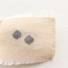 Stamped silver aspen leaf post earrings styled on tan linen