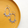 The tribal inspired feathered hoop earrings styled on a yellow plate