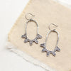 The tribal inspired feathered hoop earrings styled on tan linen