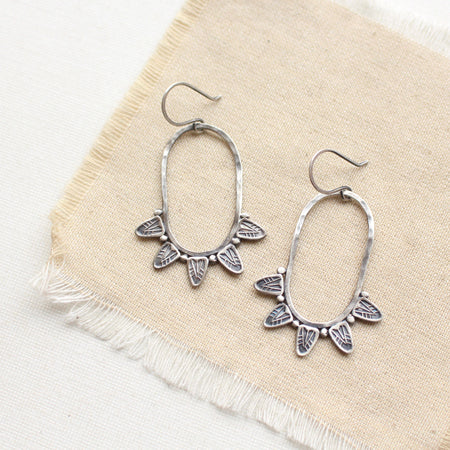 The tribal inspired feathered hoop earrings styled on tan linen