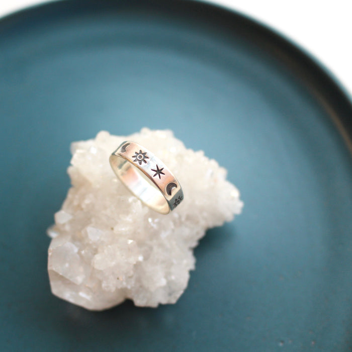 The celestial stamped ring styled on a blue plate with a crystal