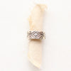 The stamped textile silver band ring is styled on a roll of tan linen