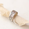 The stamped silver band ring is styled on a roll of tan linen