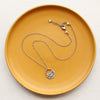 The midnight bloom necklace styled on a yellow plate to show the adjustable lobster clasp closure