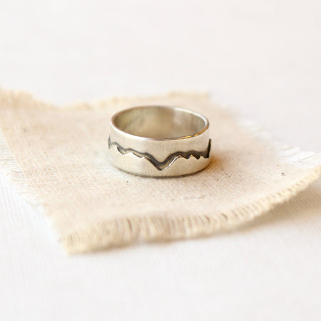 The layered silver mountain ring styled on tan linen