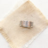 The industrial stamped silver band ring styled on tan linen