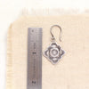 A talara winter sun earring next to a ruler for size reference