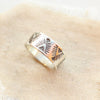 The stamped feathered triangle wide band ring styled on tan linen
