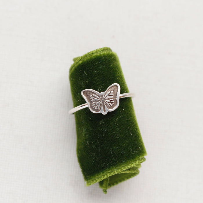 The silver butterfly stacking ring styled on green velvet