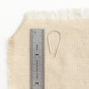 A silver hook earring next to a ruler for size reference