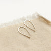 The silver hook earrings styled on tan linen