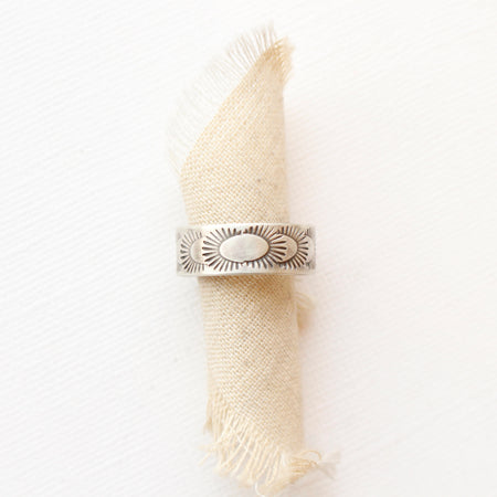 The ever expanding stamped band ring styled on a roll of tan linen