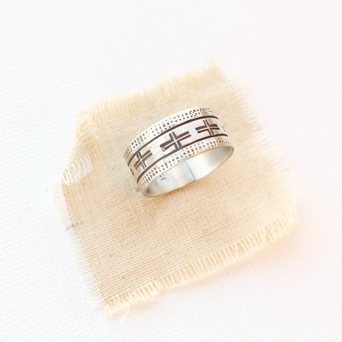 The stamped linear and cross band ring is styled on tan linen