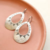 The southwest inspired pakal teardrop cutout earrings styled on a red plate