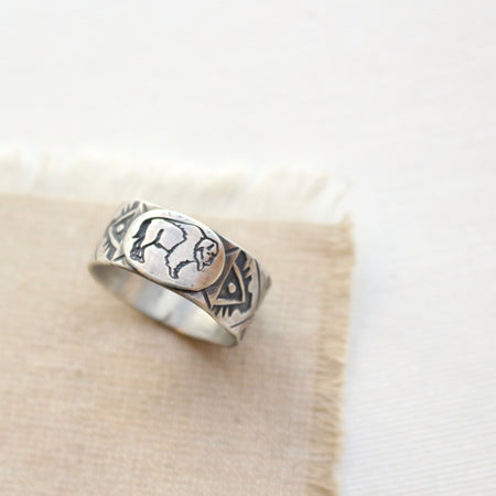 Stamped silver buffalo ring styled on tan linen