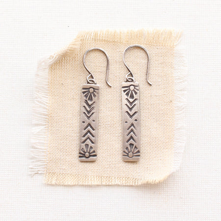 sun bar earrings on tan linen