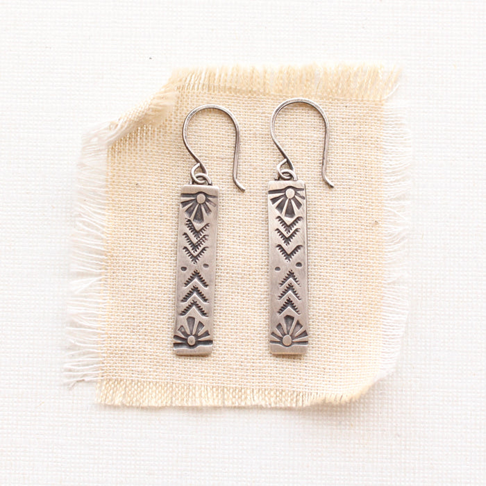 sun bar earrings on tan linen