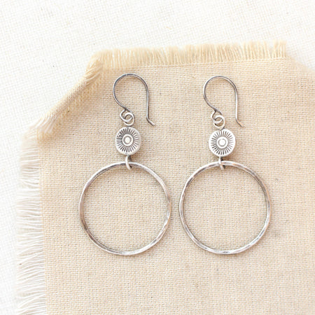 The silver talara sun hoop earrings styled on tan linen
