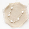 The bright silver pearl bud vine necklace styled on tan linen