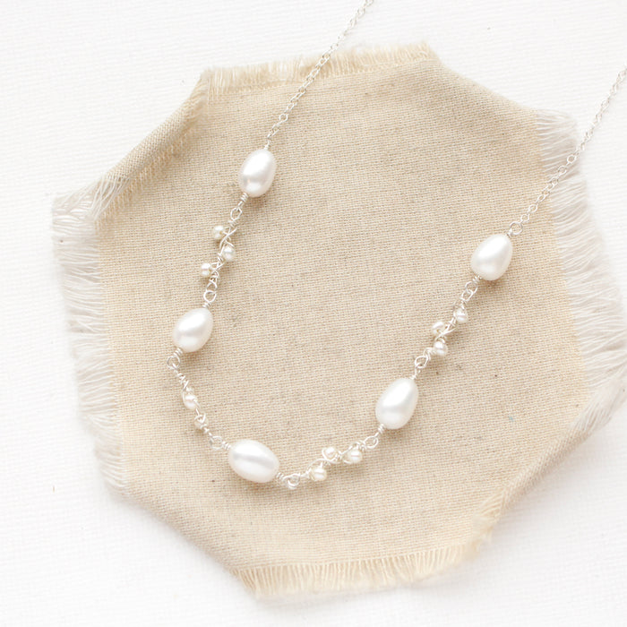 The bright silver pearl bud vine necklace styled on tan linen