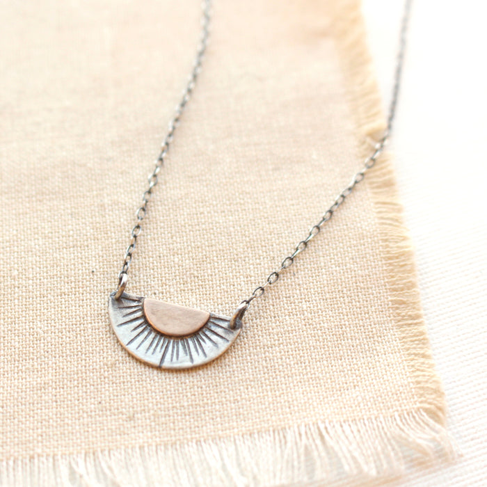 The happy half sun necklace styled on tan linen