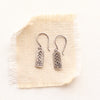 The mini sun bar earrings styled on tan linen
