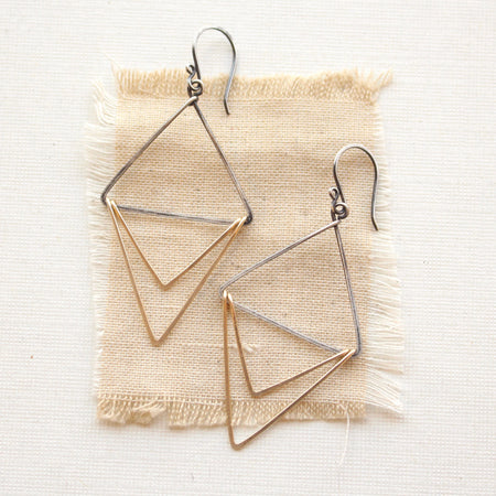 The mixed metal triple triangle hoop earrings styled on tan linen
