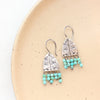 The pakal arch turquoise fringe earrings styled on a tan plate