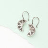 The pakal moon earrings styled on mint colored paper