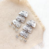 The pakal trio labradorite post earrings styled on tan linen