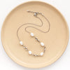 The oxidized silver pearl bud vine necklace styled on a tan plate to show the adjustable lobster clasp closure