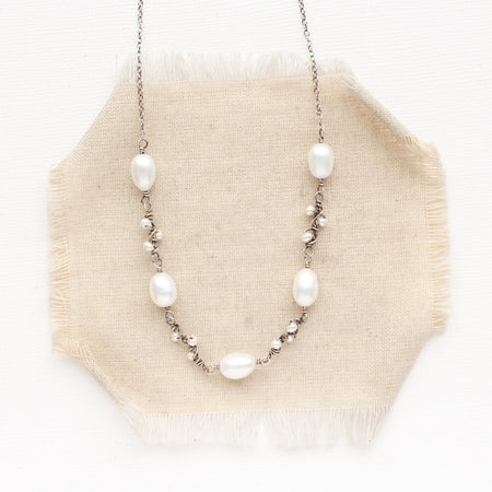 The oxidized silver pearl bud vine necklace styled on tan linen