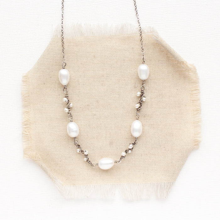 The oxidized silver pearl bud vine necklace styled on tan linen