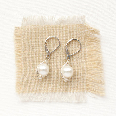 The perfect pearl silver wrapped earrings styled on tan linen