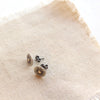 The rustic sun post earrings styled on tan linen to show the butterfly earbacks