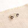 The teeny tiny heart post earrings styled on tan linen to show the butterfly earbacks