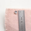 A teeny tiny heart post earring next to a ruler for size reference
